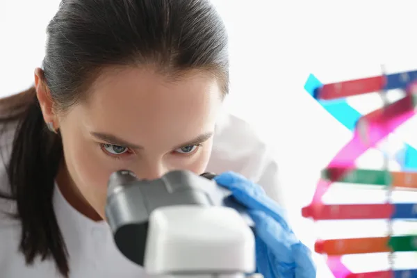 Femme scientifique regardant à travers un microscope, étudiant l'ADN — Photo