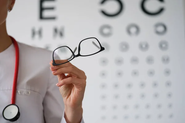La oftalmóloga doctora muestra gafas, primer plano, borrosas — Foto de Stock