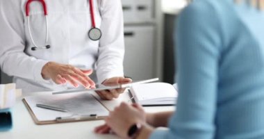 Doktor, hastanın önünde dijital tabletle ilgili bilgileri inceliyor.