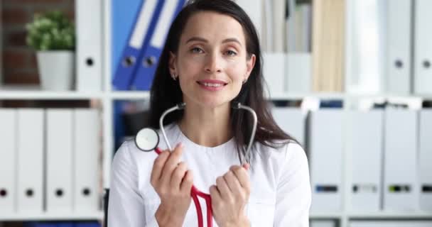 Женщина-врач надевает стетоскоп для аускультации пациента в клинике 4К кино замедленной съемки — стоковое видео