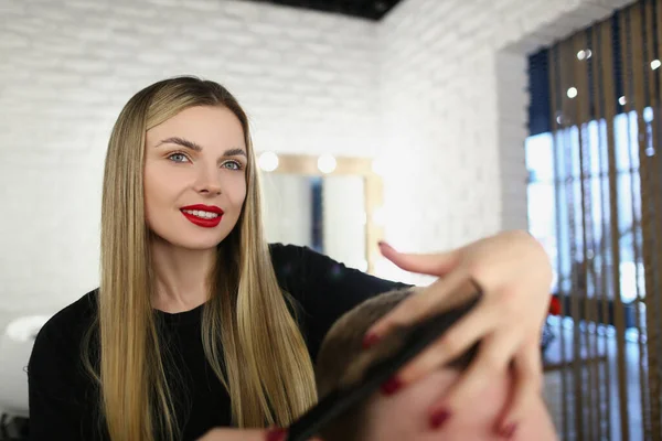 Belo cabelo jovem mestre escovação clientes cabelo com ferramenta e corte — Fotografia de Stock