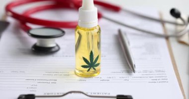 Şişede marihuana yağı ve steteskop tıbbi dokümanların üzerinde yatıyor.