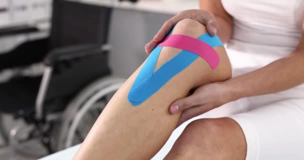Kobieta trzyma jej ból kolana z ręki z kinesio taśm 4k film slow motion — Wideo stockowe