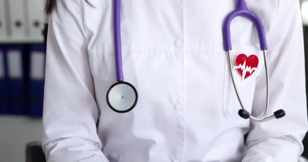 Stethoscope and heart shaped icon with electrocardiogram on doctor coat closeup 4k movie slow motion — Stock Video