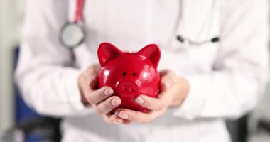 Doktor elinde parayla kırmızı kumbarayı tutuyor. 4k film yavaş çekim.