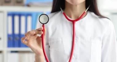 Elinde kırmızı steteskop tutan kadın doktor. Yakın çekim 4K film ağır çekim.
