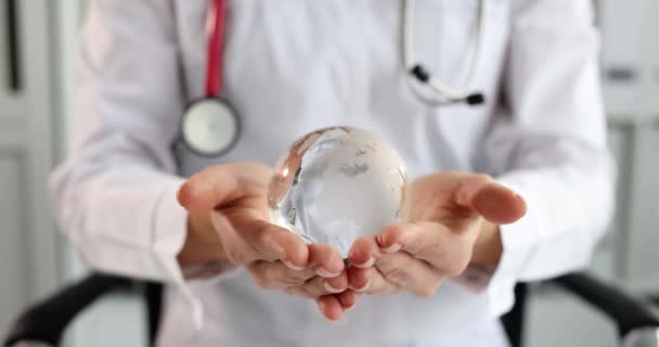 Doctor holding glass globe with world map 4k film slow motion — Stock video