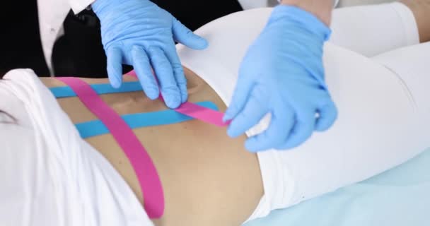 Läkare limmar kinesio tejp till patienten ryggraden slow motion 4k film — Stockvideo