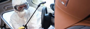 Koruyucu giysili dezenfektan ve gözlüklü araba dezenfektanı
