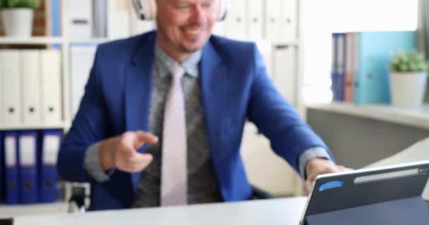 Бізнесмен одягає навушники перед цифровим планшетом і починає танцювати в офісі 4k фільм повільний рух — стокове відео