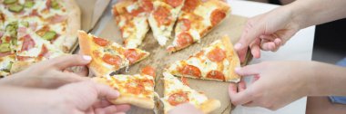 Bir sürü yetişkin ve çocuk eli iştah açıcı pizza dilimleri alıyor.