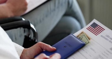 Sandalyelerde oturan ve vize başvurusu formu dolduran bir grup insan.