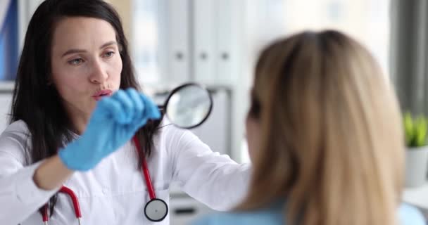 Женщина-врач смотрит на лицо пациента через увеличительное стекло 4К фильм замедленной съемки — стоковое видео