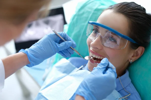 診療所で歯科器具を用いて女性患者の口腔を調べる医師 — ストック写真