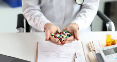 Kadın doktor, klinikte elinde bir sürü renkli kapsül tutuyor. Ağır çekim.