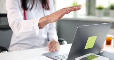 Kadın doktor dizüstü bilgisayarın kapağını yavaşça kapatıyor.