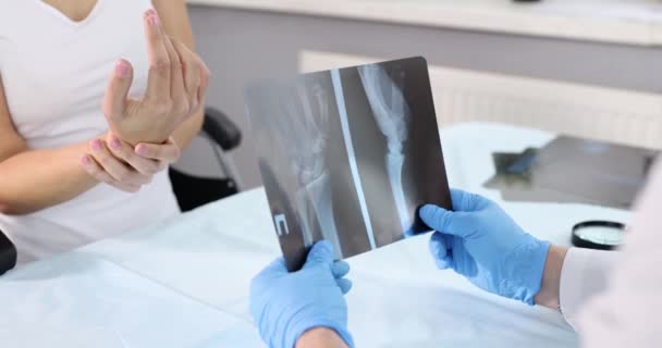 Doctor mirando la radiografía de la mano delante del paciente enfermo 4k película cámara lenta — Vídeo de stock