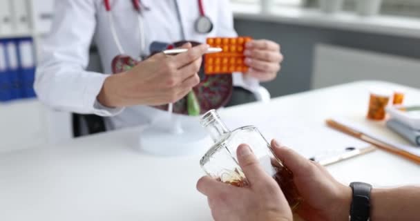 Médico mostrando paciente con adicción al alcohol modelo de hígado artificial y ampolla con píldoras 4k película cámara lenta — Vídeo de stock