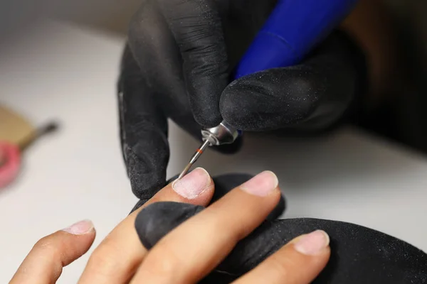 Mistrz paznokci za pomocą narzędzia do czyszczenia kobiet klientów paznokcie w studiu piękności — Zdjęcie stockowe