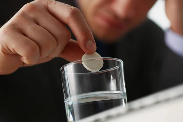 Müder Mann steckte Tablette in Glas mit Wasser, um Kopfschmerzen wegen großer Arbeitsbelastung zu stoppen — Stockfoto