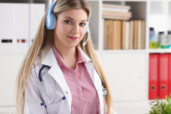 Médico loira bonita falando com paciente sobre fone de ouvido sem fio aconselha problema médico — Fotografia de Stock