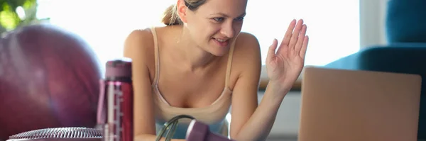 Mulher sorridente cumprimenta treinador de fitness através do monitor do laptop — Fotografia de Stock