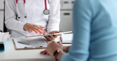 Doktor elinde tablet tutuyor ve hasta muayenesinin sonuçlarını inceliyor.