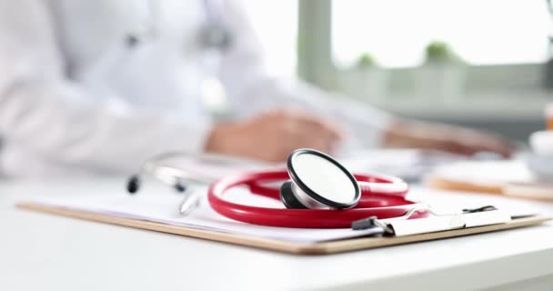 Stetoskop terletak pada dokumen medis di latar belakang dokter yang bekerja — Stok Video