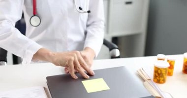 Doktor iş yerinde ağır çekimde 4K film izlerken dizüstü bilgisayarı açar.