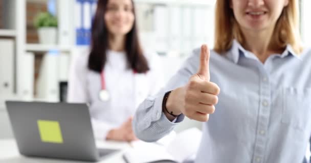 Patienten håller tummen upp mot bakgrund av leende läkare slow motion 4k film — Stockvideo