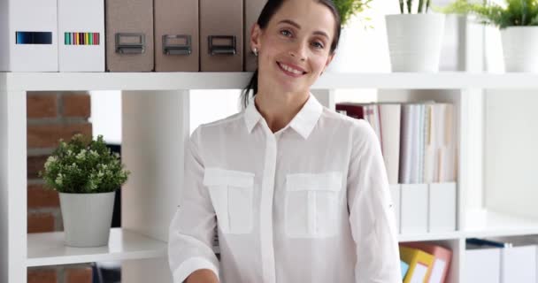 Молодая улыбающаяся деловая женщина складывает руки на груди, стоя в офисе замедленной съемки 4К фильма — стоковое видео