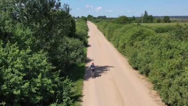 Férfi kerékpáros kerékpározik a vidéki úton városon kívül — Stock videók