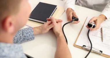 Doktor klinikteki hastaya kan basıncını ölçüyor.