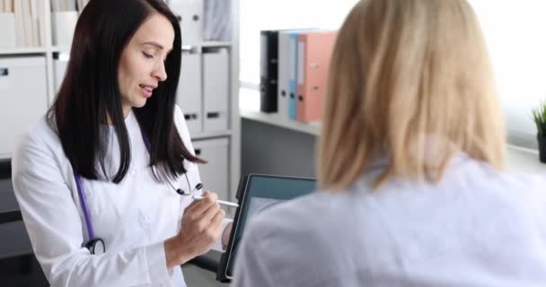 Γυναίκα γιατρός δείχνει ακτινογραφία των πνευμόνων σε ψηφιακό δισκίο στον ασθενή 4k ταινία αργή κίνηση — Αρχείο Βίντεο