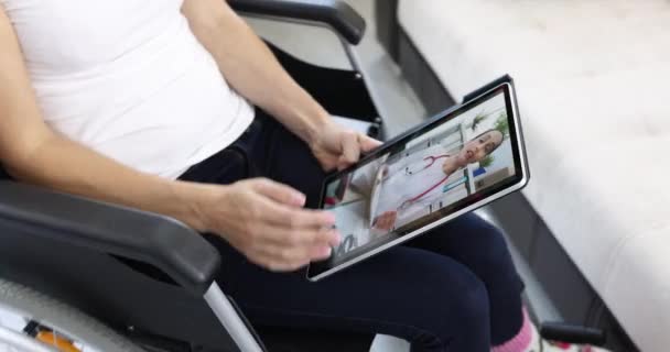 휠체어에 앉아 디지털 태블릿 4k 영화를 이용해 원격으로 의사와 의사소통을 하는 장애인 여성 — 비디오