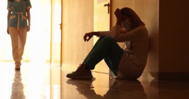 Koruyucu maskeli kadın doktor klinikte yerde ağlıyor ağır çekimde.