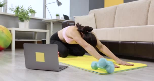 Jeune femme faisant des exercices de gymnastique pour étirer la colonne vertébrale sur le tapis à la maison — Video