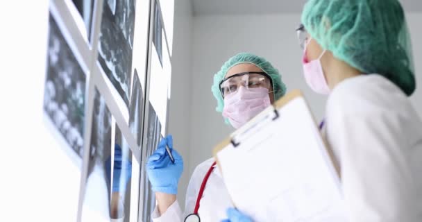 Médicos con gafas y máscaras mirando rayos X en la clínica 4k película cámara lenta — Vídeos de Stock