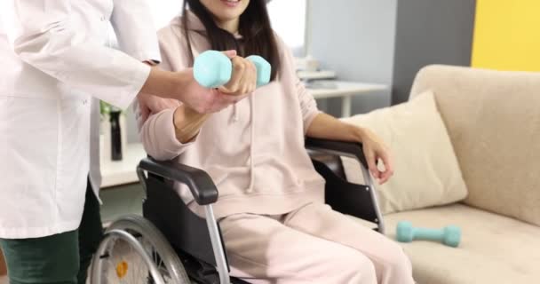 Resuscitator aiuta la donna in sedia a rotelle a fare esercizi con manubri — Video Stock