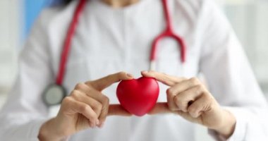 Doktor kardiyolog klinikte kırmızı oyuncak kalbi tutuyor.