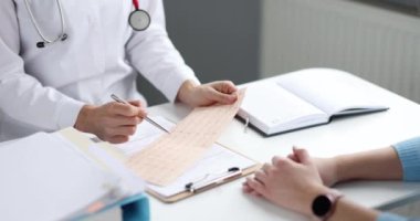 4K numaralı hasta ağır çekimde elektrokardiyogramı inceleyen doktor.
