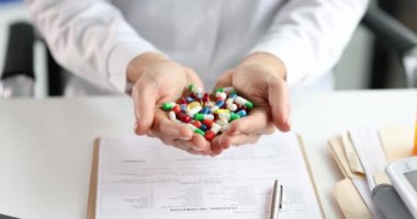 Klinikte bir avuç dolusu renkli tıbbi kapsül tutan doktor. Yakın çekim 4k film, ağır çekim.