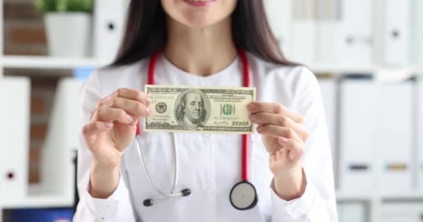 Mujer médico plegable billete de dólar y poner en uniforme bolsillo primer plano 4k película cámara lenta — Vídeos de Stock