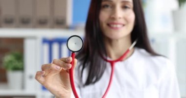 Klinikte kırmızı steteskop tutan kadın. Yakın çekim 4K film ağır çekim.