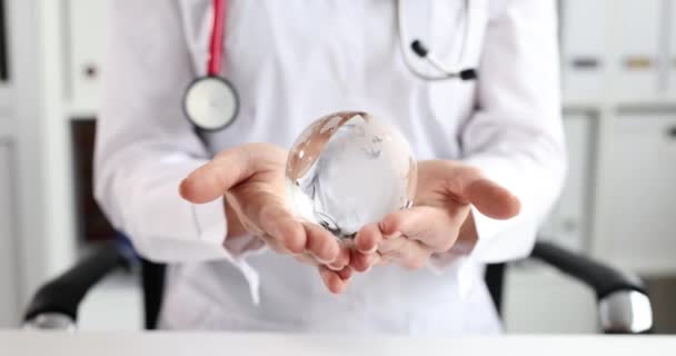 Klinikte elinde dünya haritası olan cam küreyi tutan doktor. — Stok video