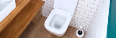 Banyo arka planında duran açık kapaklı beyaz klozet.