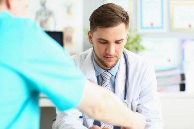 Erkek doktor masada oturuyor, aşağı bakıyor, yakın plan.