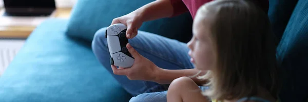 Mamá y su hija sentado en el sofá y la celebración de joysticks ordenador primer plano —  Fotos de Stock