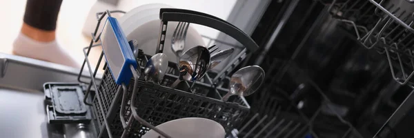 Білі тарілки та столові прибори у відкритій посудомийній машині крупним планом — стокове фото