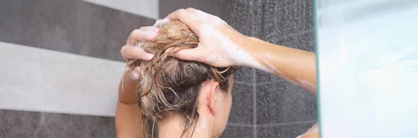 Jovem mulher lavando o cabelo com xampu no chuveiro — Fotografia de Stock